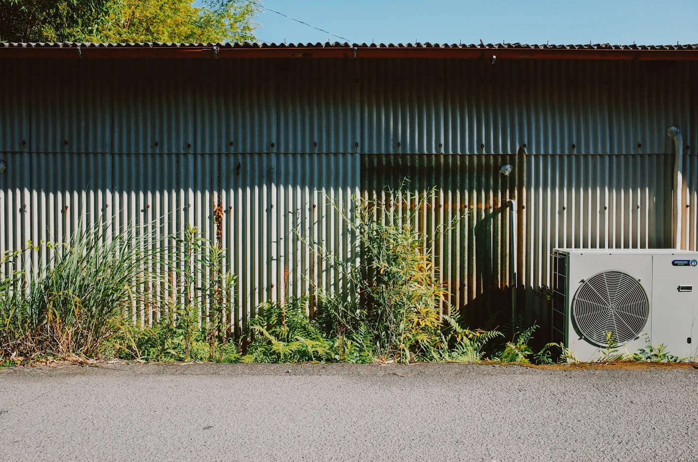 Air conditioning unit fixed to a corrugated metal building wall