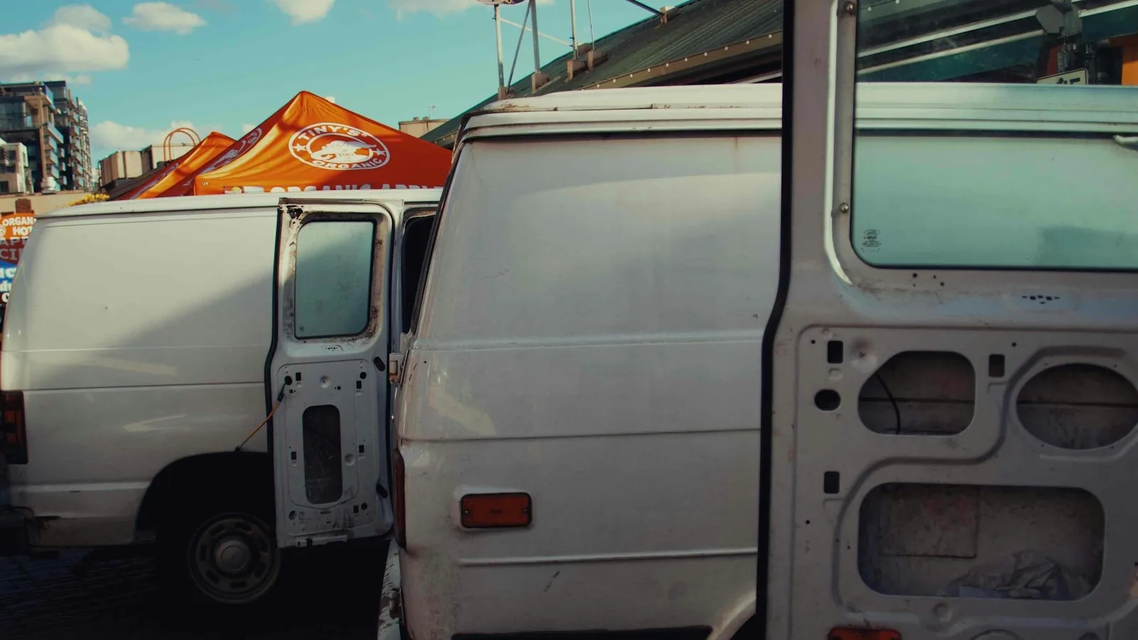 Two white contractor work vans parked side by side under a blue sky