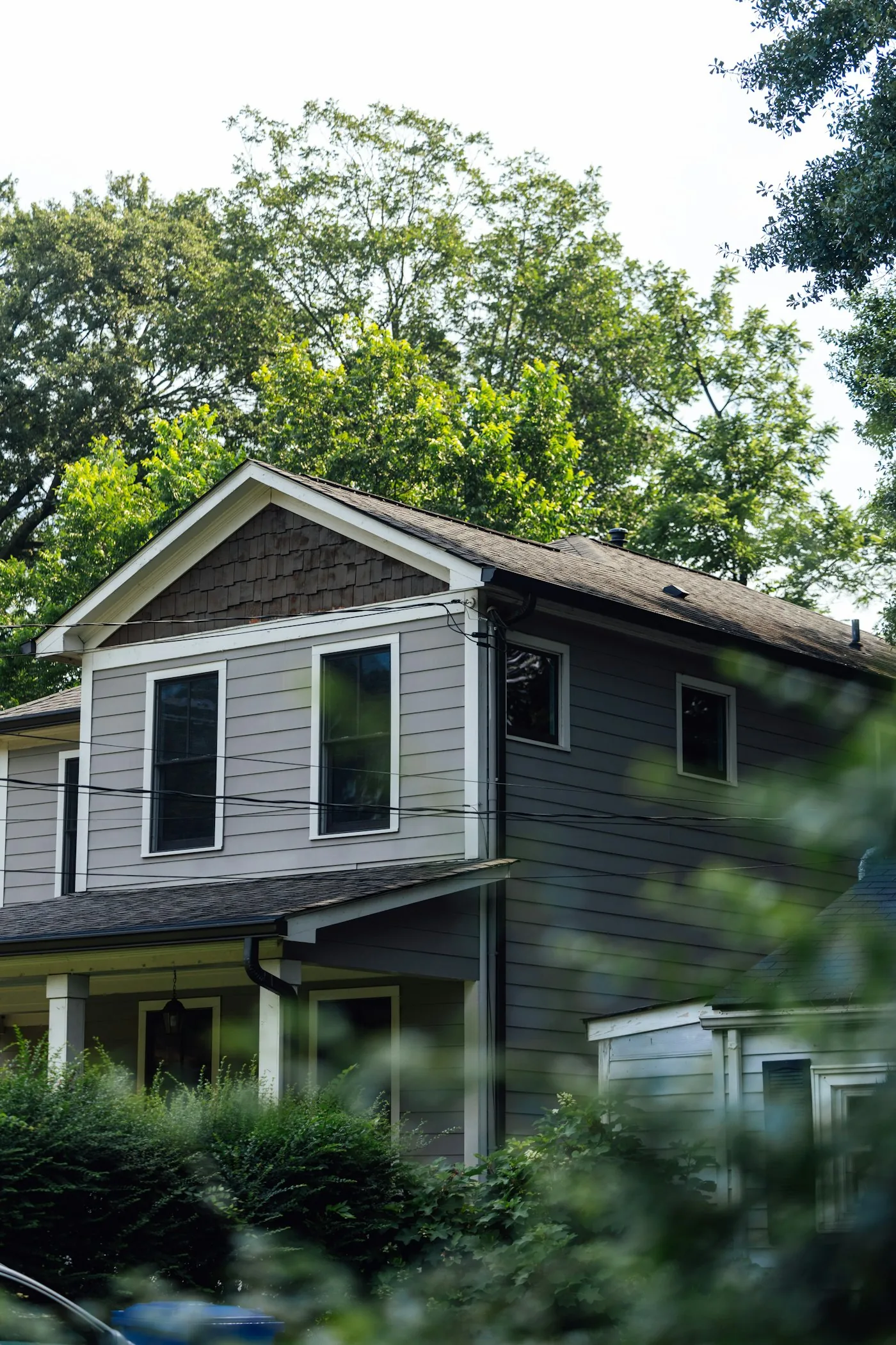 Residential home with a shingled roof surrounded by trees