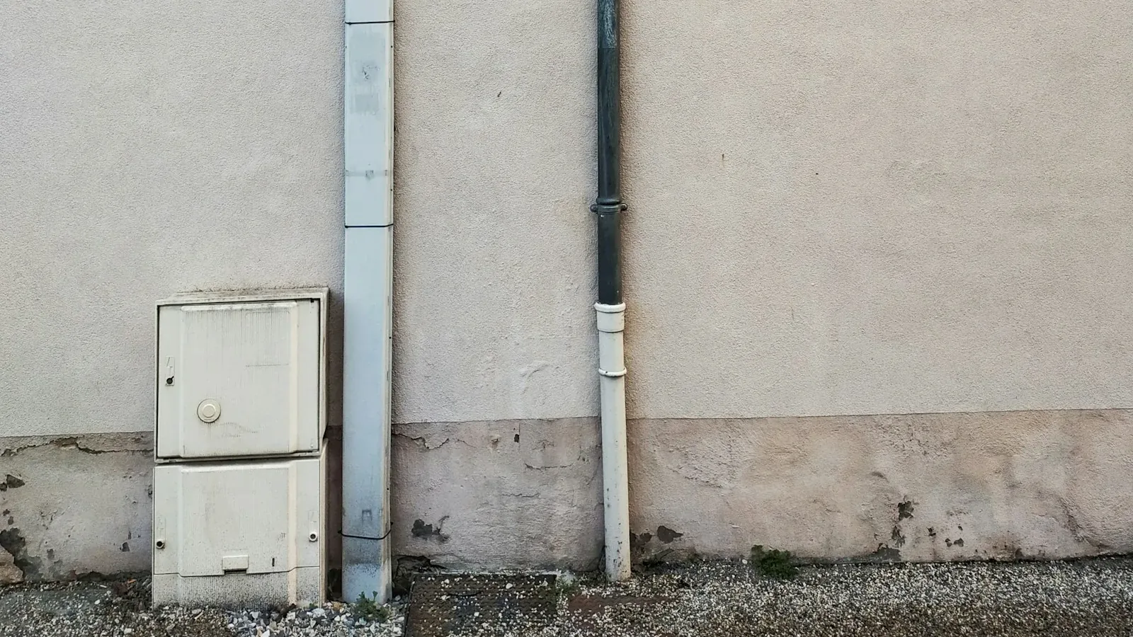 Utility boxes and conduit running down the exterior wall of a building