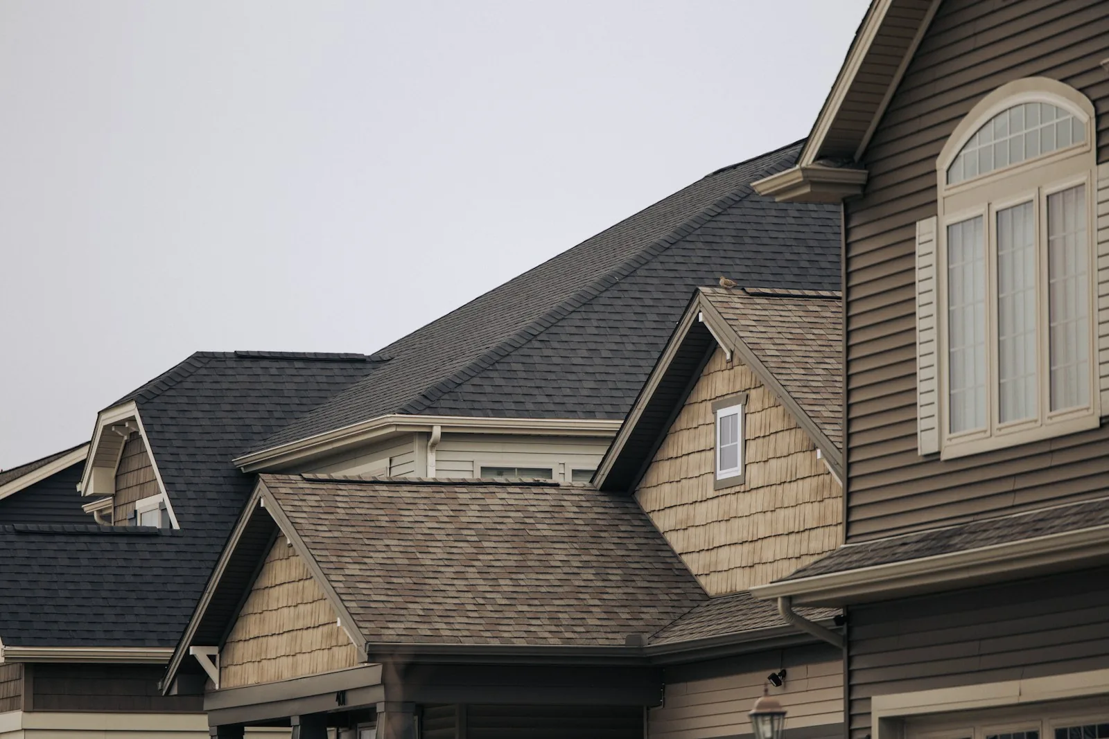 Two suburban rooflines of aging asphalt shingles with dormers and cedar shake gables